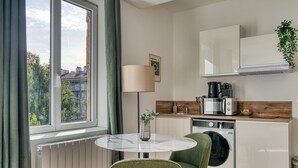 Eine kleine Küche mit einem runden Tisch, einer Waschmaschine und einer Kaffeemaschine.