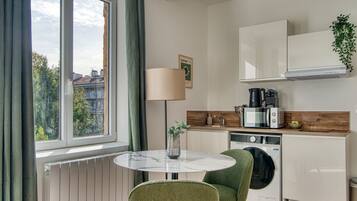 A compact kitchen with a round table, a washing machine, and a coffee maker.