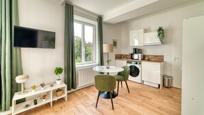 Eine moderne Küche mit Einbauofen, Mikrowelle und Spüle. Ein Esstisch mit Stühlen und ein an der Wand montierter Fernseher sind ebenfalls vorhanden.