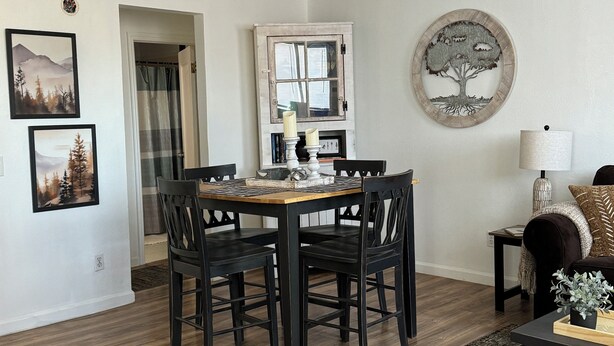 A dining area with a wooden table and chairs, a fireplace with a window, and a round wall decoration.