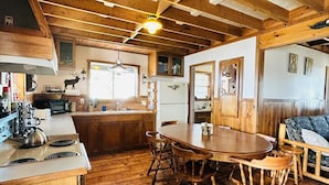 A rustic kitchen with wooden cabinets, a dining table, and a built-in oven. - Delightful 3-bedroom house with AC in Usk (Usk)
