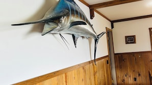 A room with wooden paneling, a mounted fish on the wall, and a framed picture on the wall. - Delightful 3-bedroom house with AC in Usk (Usk)