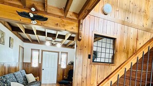 A wooden interior with a staircase, a wooden bench, a cushioned sofa, and a door leading to another room. - Delightful 3-bedroom house with AC in Usk (Usk)