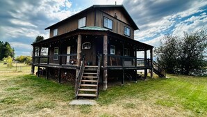 A two-story wooden house with a porch, a staircase leading to the entrance, and a grassy yard. - Delightful 3-bedroom house with AC in Usk (Usk)