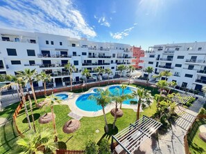 Guests can enjoy a refreshing swim in the pool surrounded by lush palm trees and a manicured lawn.