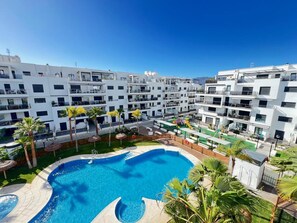 Enjoy a refreshing swim in the central courtyard pool surrounded by lush palm trees and a children's play area.