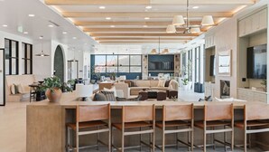A spacious, well-lit lounge area with a central seating area, multiple tables, and chairs. - Amazing Deluxe 2BR Pool/Gym/Htub (Salt Lake City)