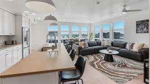 A modern kitchen with a central island, dining area, and a living room with a sofa and coffee table. - Amazing Deluxe 2BR Pool/Gym/Htub (Salt Lake City)