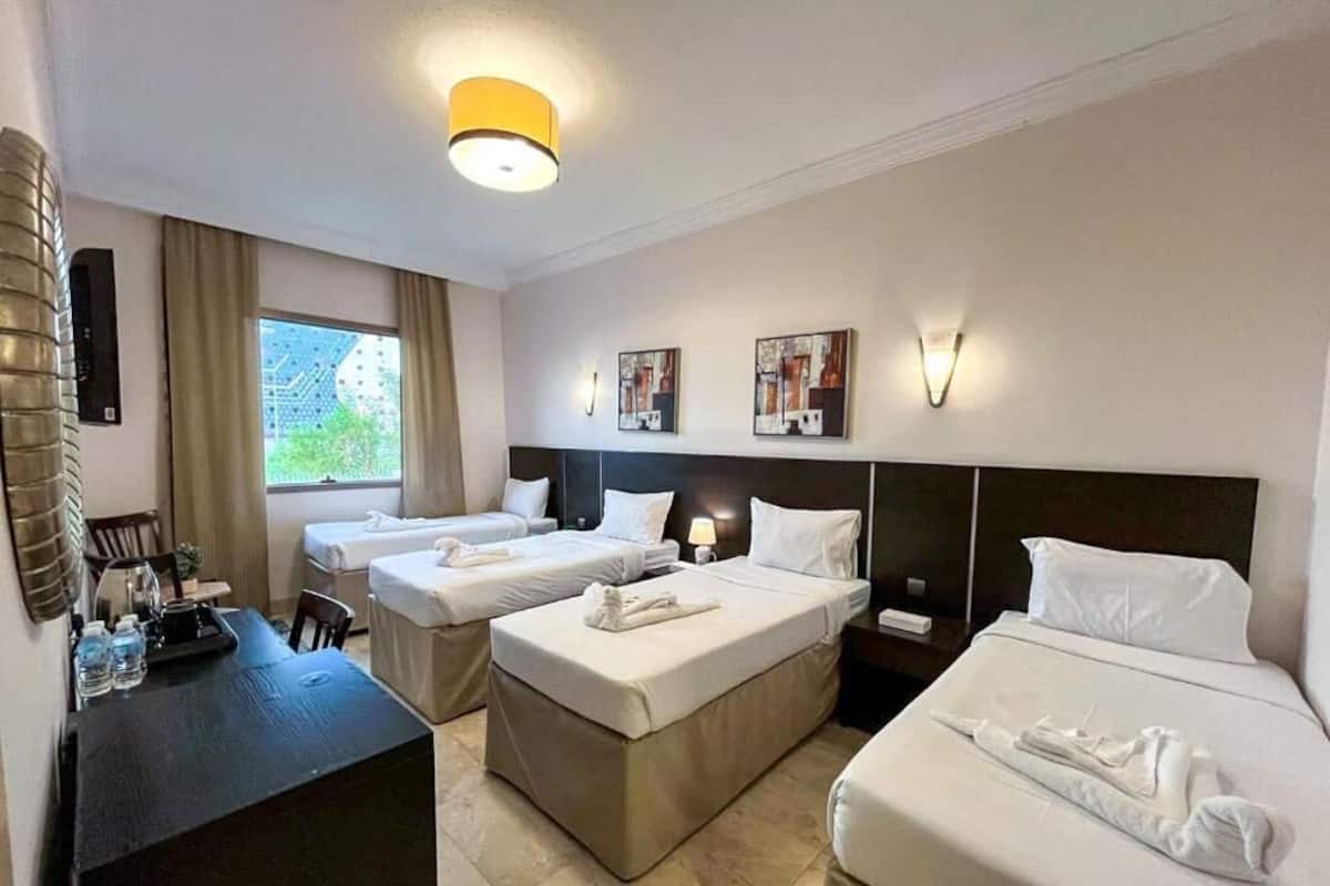 A hotel room with two beds, a desk, and a window.