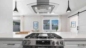 Una cocina moderna con una isla central, electrodomésticos de acero inoxidable e iluminación colgante.