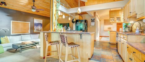 Une cuisine moderne avec des meubles en bois, un îlot central et des luminaires suspendus.