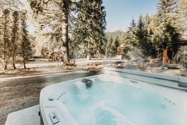 Un jacuzzi en un área boscosa con vistas a montañas al fondo.