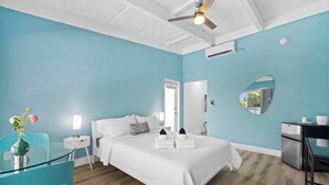 A hotel room with a bed, a desk, a chair, a small table, a mirror, and a vase with flowers. - Chic Hotel in Vibrant Miami with Free Pool, WiFi, Coffee and Bagels - BOOK NOW! (Miami)