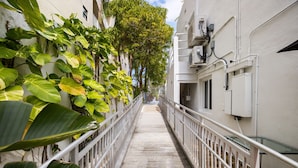 A narrow, covered walkway flanked by white buildings and lush green plants. - Chic Hotel in Vibrant Miami with Free Pool, WiFi, Coffee and Bagels - BOOK NOW! (Miami)