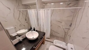 Un bagno moderno con lavabo in marmo, una vasca e un water.