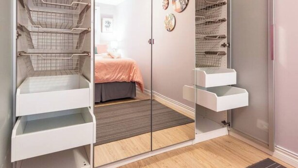 Un dormitorio con una cama, un armario con varios estantes y un espejo.