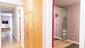 Un apartamento moderno con un armario de madera, una puerta de cristal y una cocina visible al fondo.