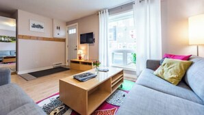 Una sala de estar moderna con un sofá, una mesa de centro y un televisor montado en la pared.
