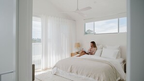 A bedroom with a bed, a nightstand, a lamp, and a ceiling fan.