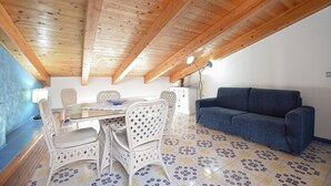 A room with a wooden ceiling, a dining table with chairs, a sofa, and patterned floor tiles. - Amazing apartment in Santa Maria di Castell (Santa Maria di Castell)