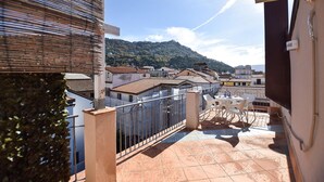A balcony with a tiled floor, a metal railing, and a view of a hillside with buildings. - Amazing apartment in Santa Maria di Castell (Santa Maria di Castell)