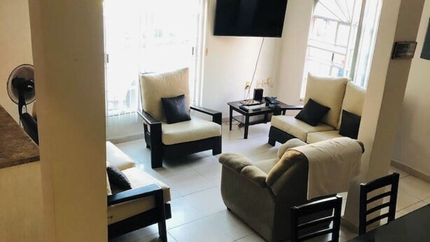 Un salon avec un canapé, des fauteuils, une table basse et un téléviseur.