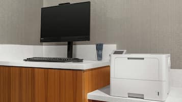 A modern office setup with a flat-screen monitor, keyboard, and a white printer on a speckled countertop.