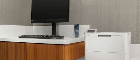 A modern office setup with a flat-screen monitor, keyboard, and a white printer on a speckled countertop.