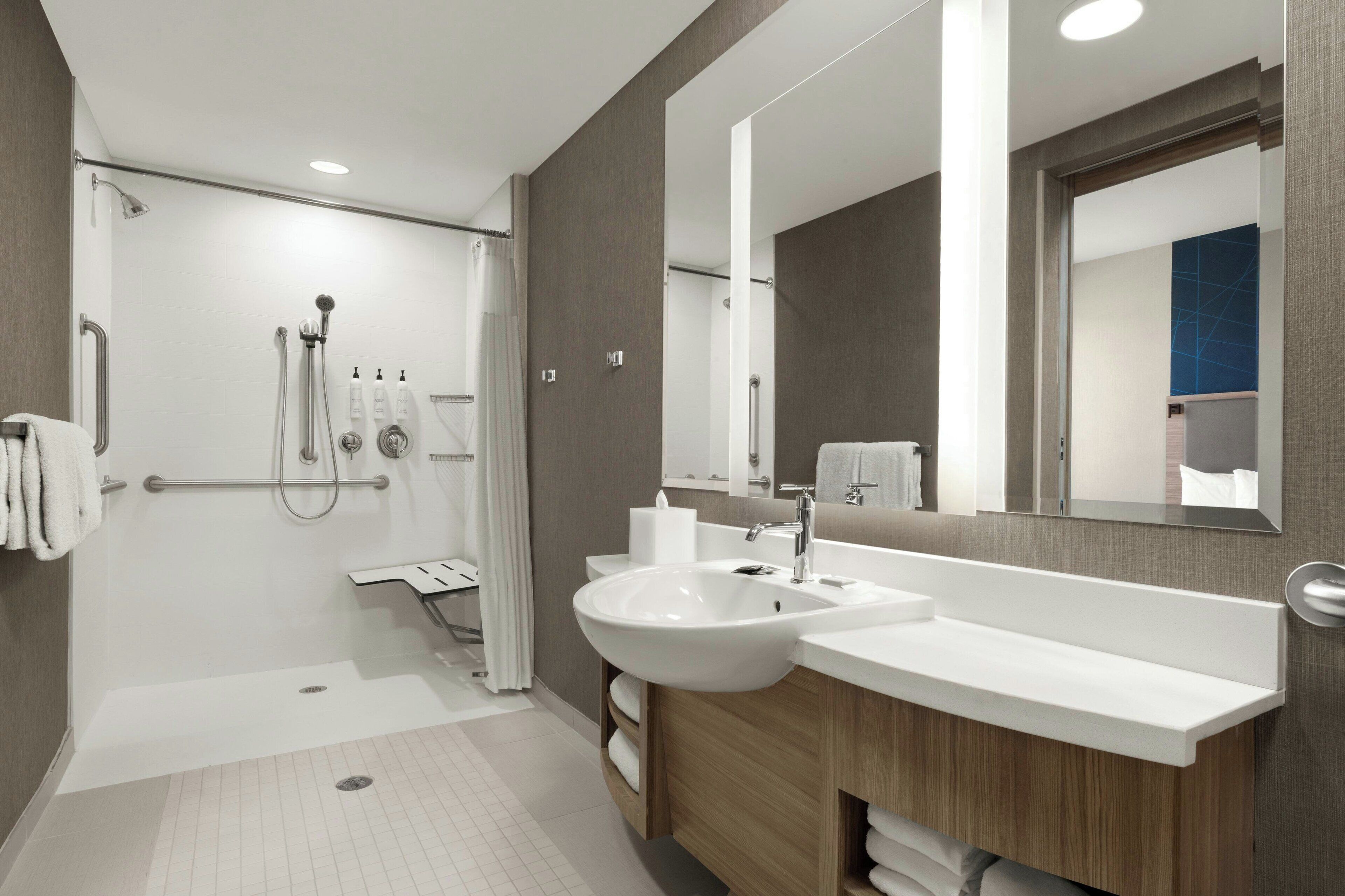 A modern bathroom with a walk-in shower, a double sink vanity, and a large mirror.