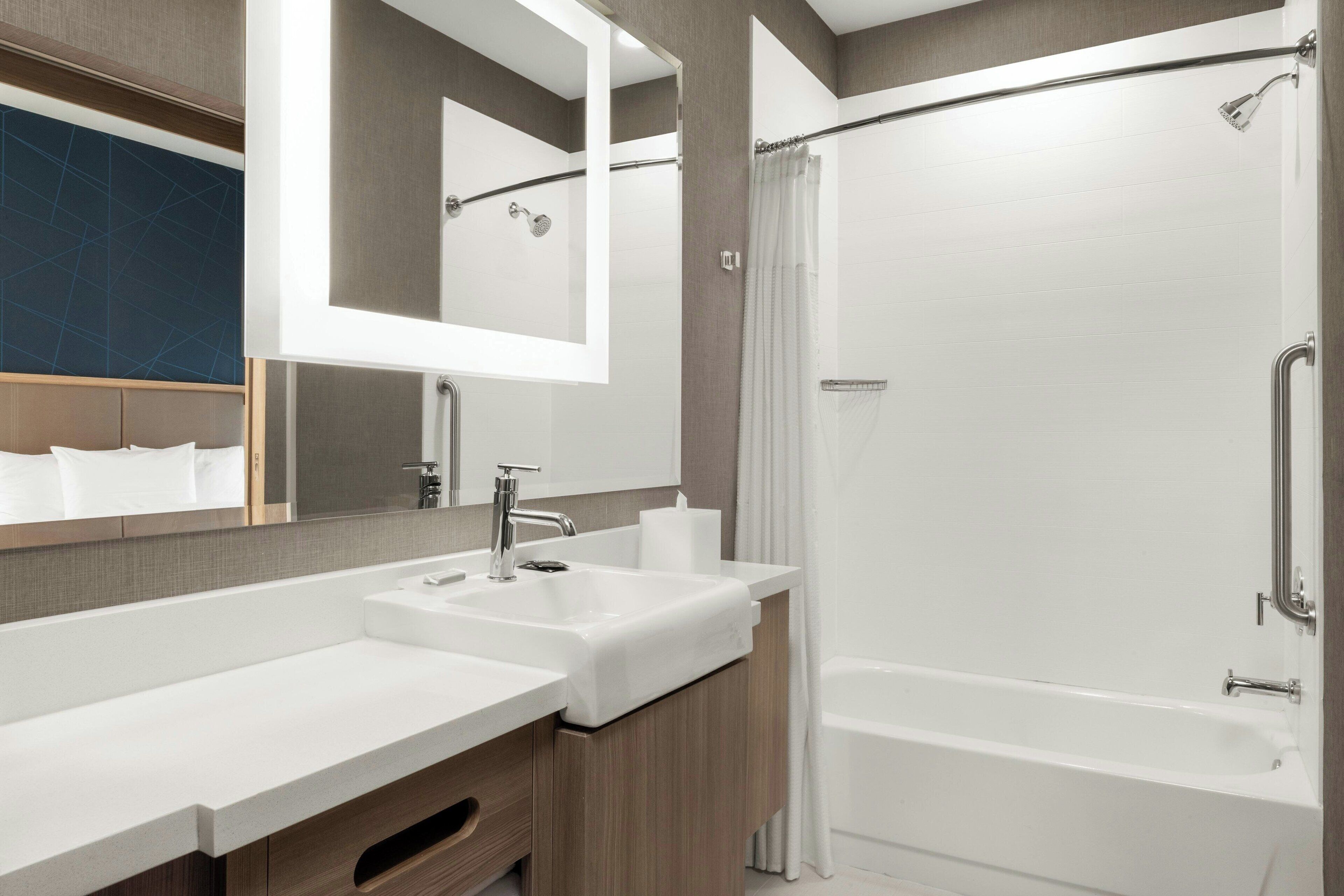 Un baño moderno con dos lavamanos, ducha y un espejo grande.