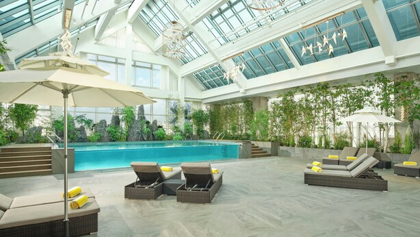 A spacious indoor pool area with multiple lounge chairs and umbrellas, a large glass ceiling, and a view of the pool. - The Link Seoul, A Tribute Portfolio Hotel (Seoul)