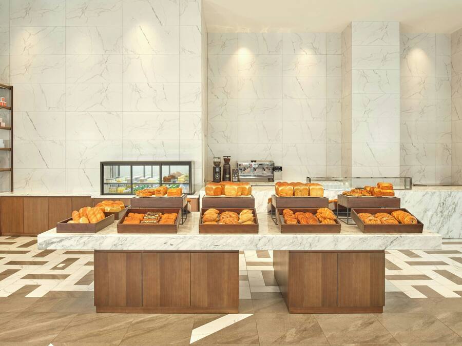A breakfast buffet with various pastries and bread, marble walls, and wooden cabinets.