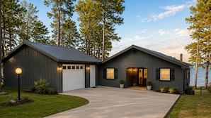 Una casa a due piani con garage, vialetto e vista su un lago.