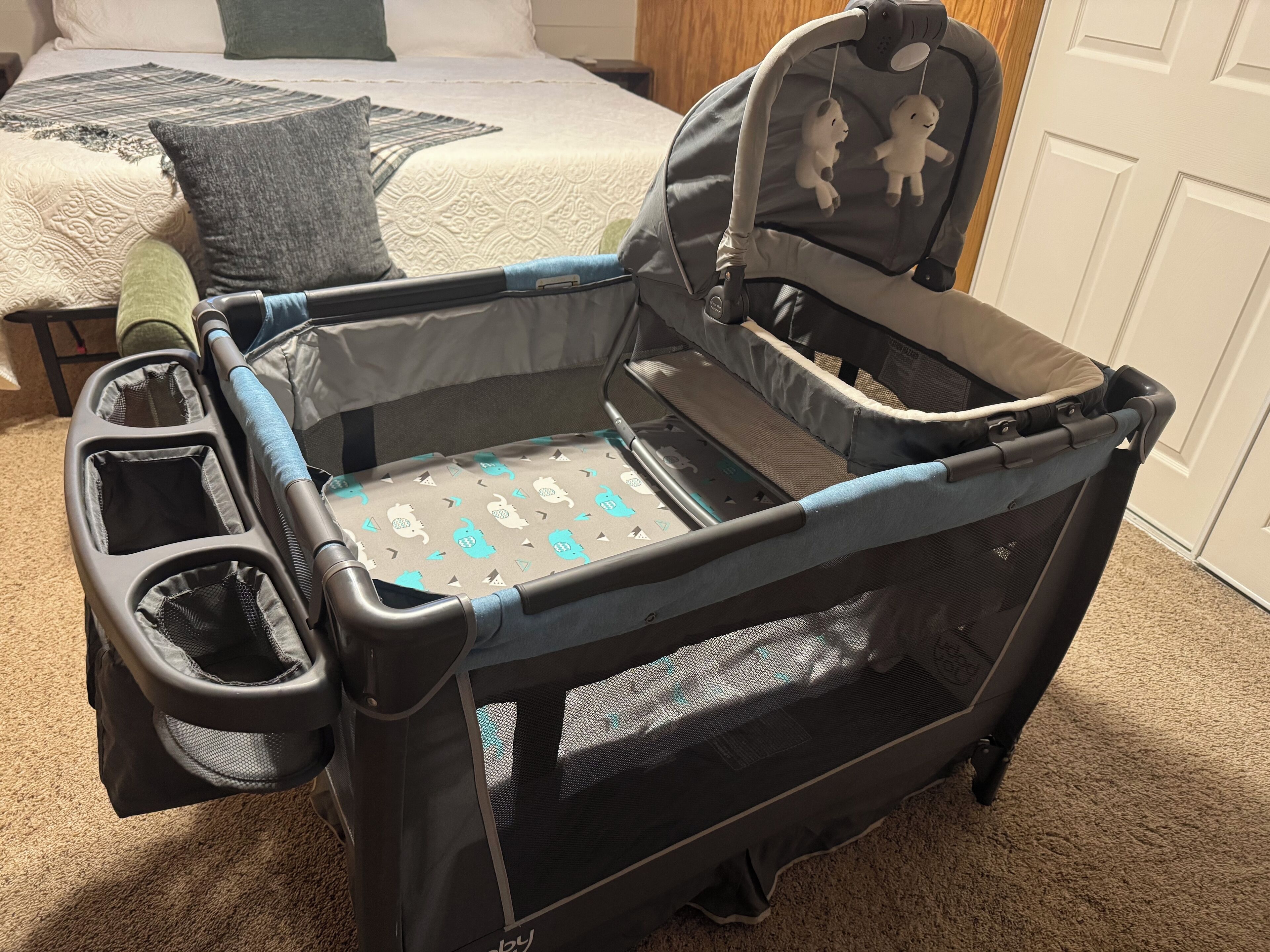 A black baby stroller with a mesh seat and a tray table, positioned on a carpeted floor.