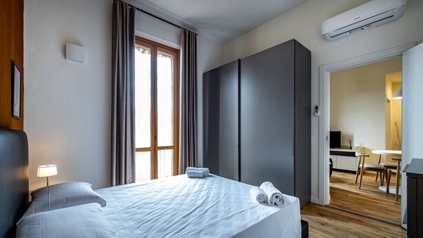 Une chambre d’hôtel équipée d’un lit, d’un bureau, d’une chaise et d’un appareil de climatisation.
