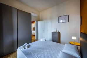 A hotel room with a bed, a nightstand with a lamp, a wardrobe, and a framed word on the wall.