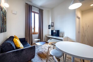A modern living room with a sofa, a dining table, and a TV.
