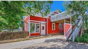 Una casa roja con un porche y una escalera que lleva a una terraza.