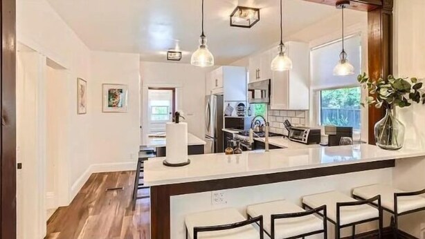 Una cocina moderna con una isla central, asientos tipo bar e iluminación colgante.