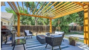 Un patio cubierto al aire libre con pérgola, zona de estar y barbacoa.