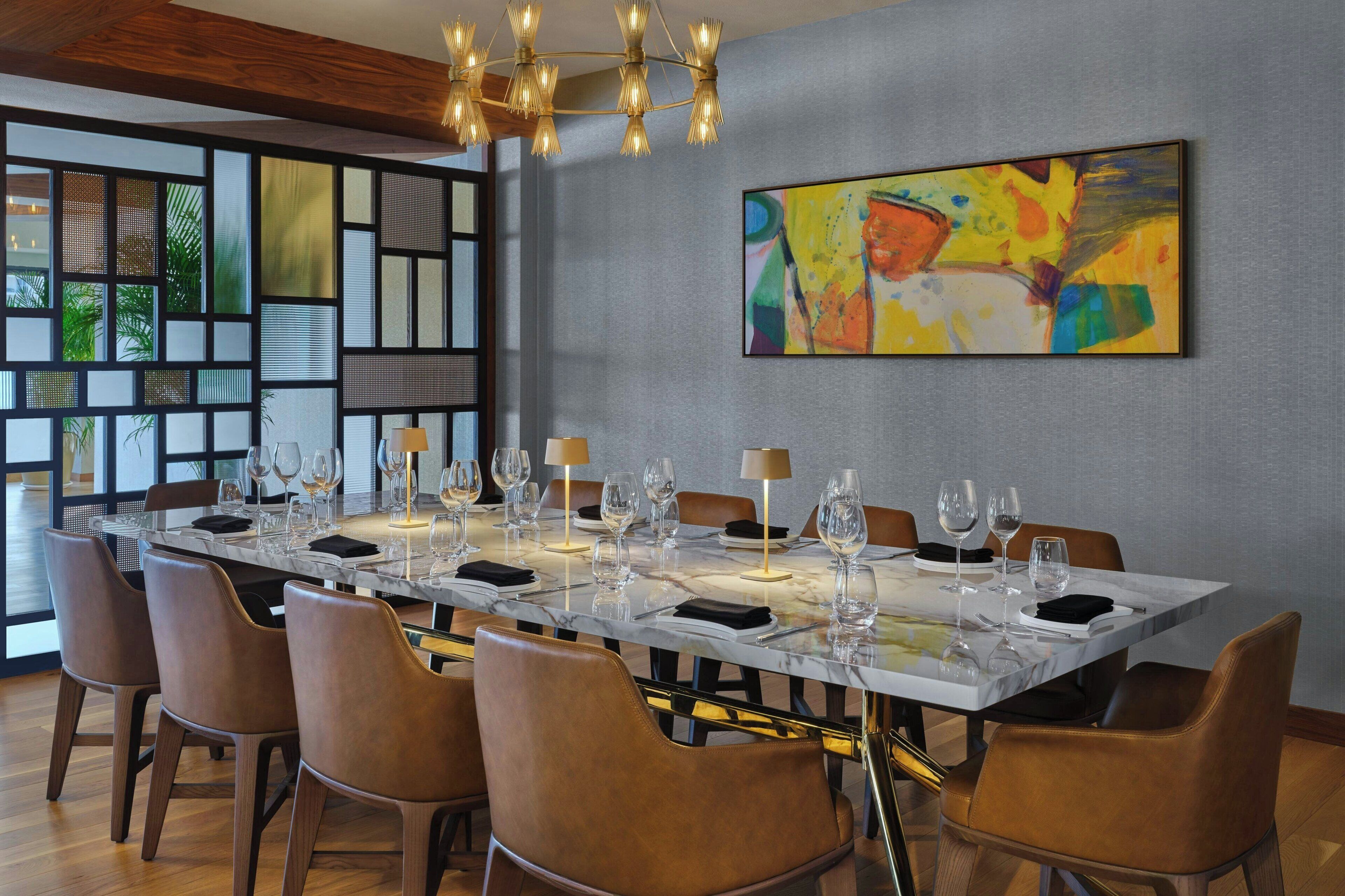 Un comedor con una larga mesa dispuesta para seis personas, rodeada de seis sillas.
