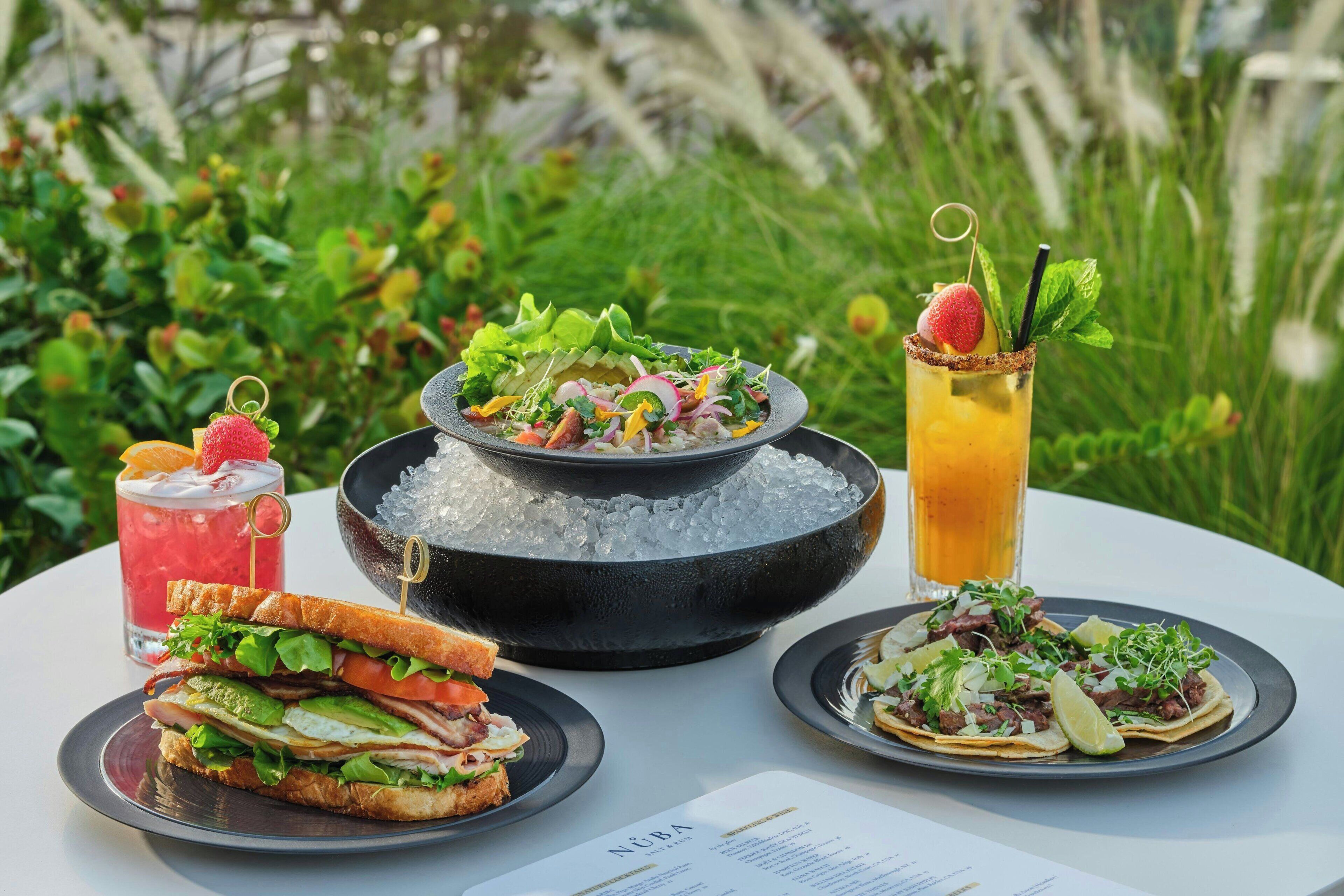 Una mesa con ensalada, un sándwich, una bebida y un tazón de helado.