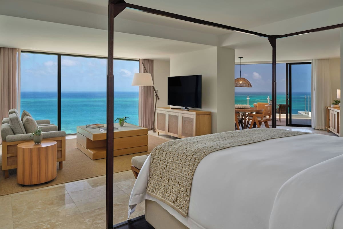 Een ruime slaapkamer met een groot bed, een televisie en uitzicht op de oceaan.