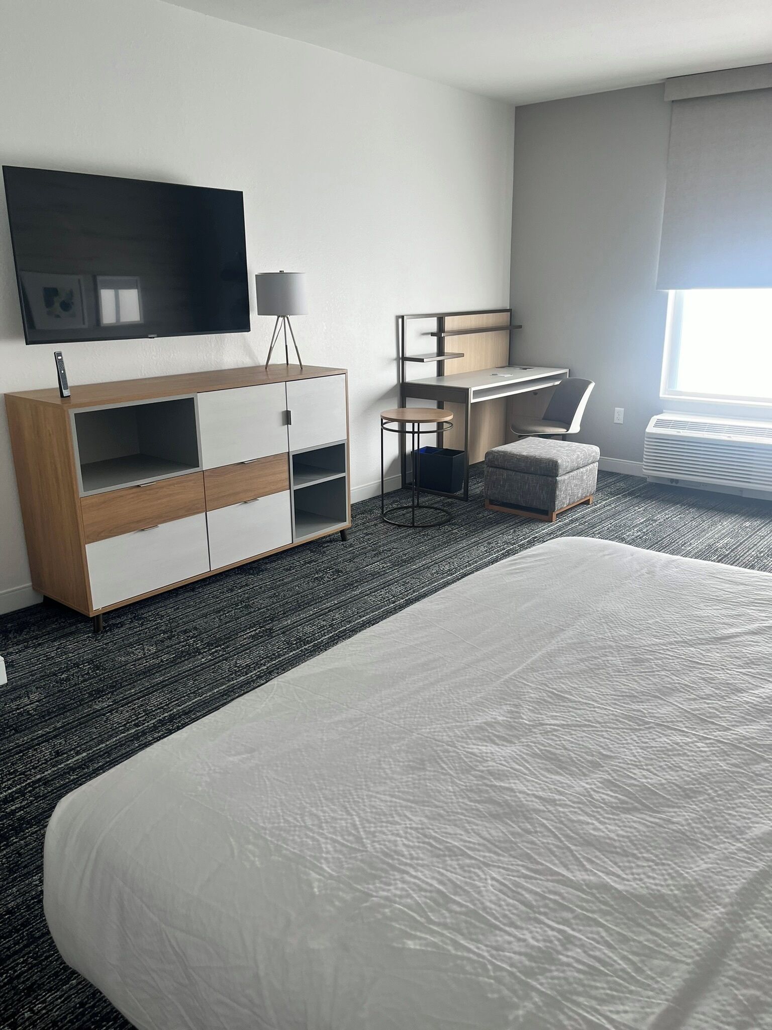 Quarto de hotel com uma cama grande, uma mesa, uma cadeira, uma televisão e um guarda-roupa.