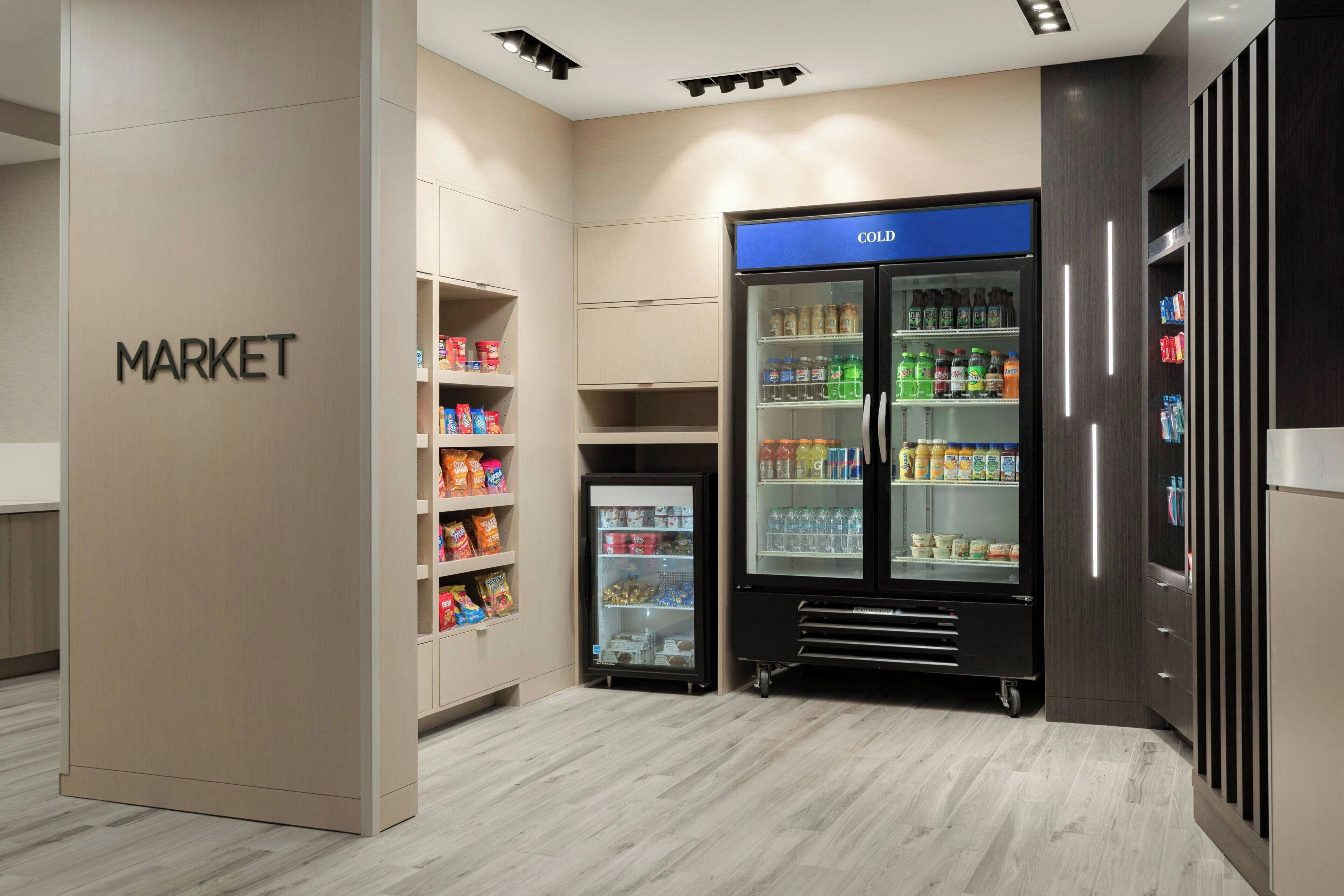 Uma área de mercado moderna, com balcões refrigerados e prateleiras repletas de diversos produtos.