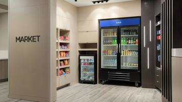 Uma área de mercado moderna, com balcões refrigerados e prateleiras repletas de diversos produtos.
