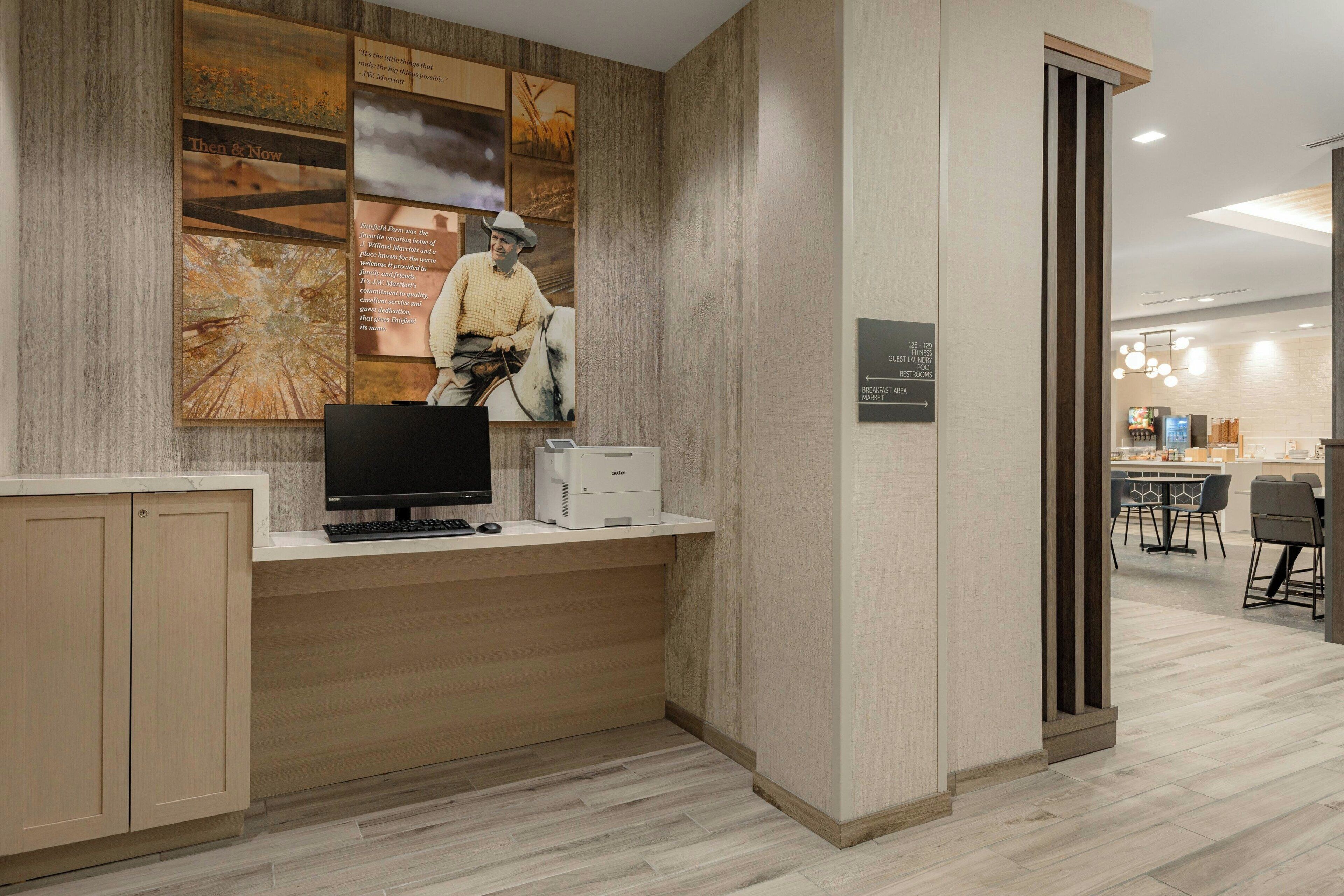 A reception desk with a computer, printer, and informational posters.