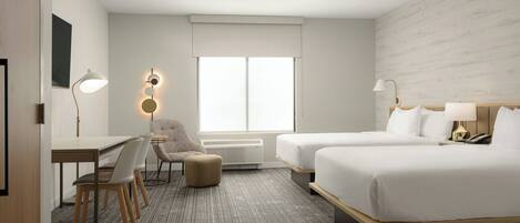 A hotel room with two beds, a desk, a chair, a lamp, and a large window.