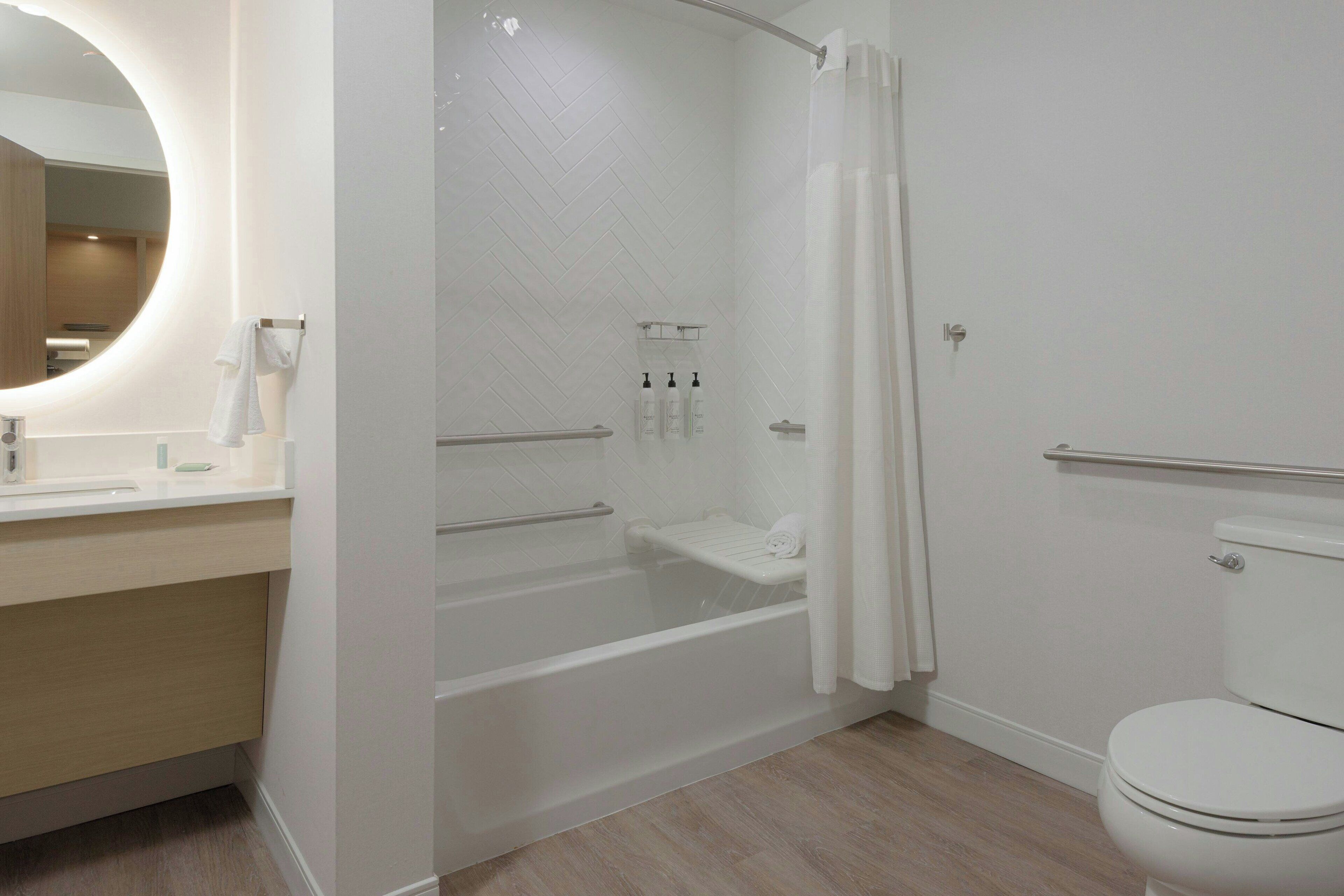 A modern bathroom with a bathtub, toilet, and a shower area.