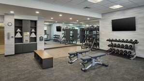 Ein modernes Fitnessstudio mit Krafttrainingsgeräten, Bänken und einer Spiegelwand.